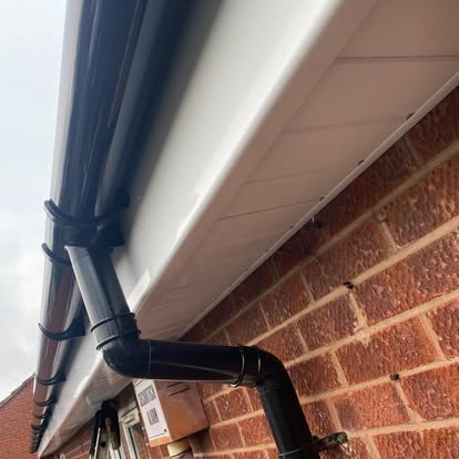 Black round guttering and downpipe fitted to brick property by LDF Fascia & Guttering, West Midlands