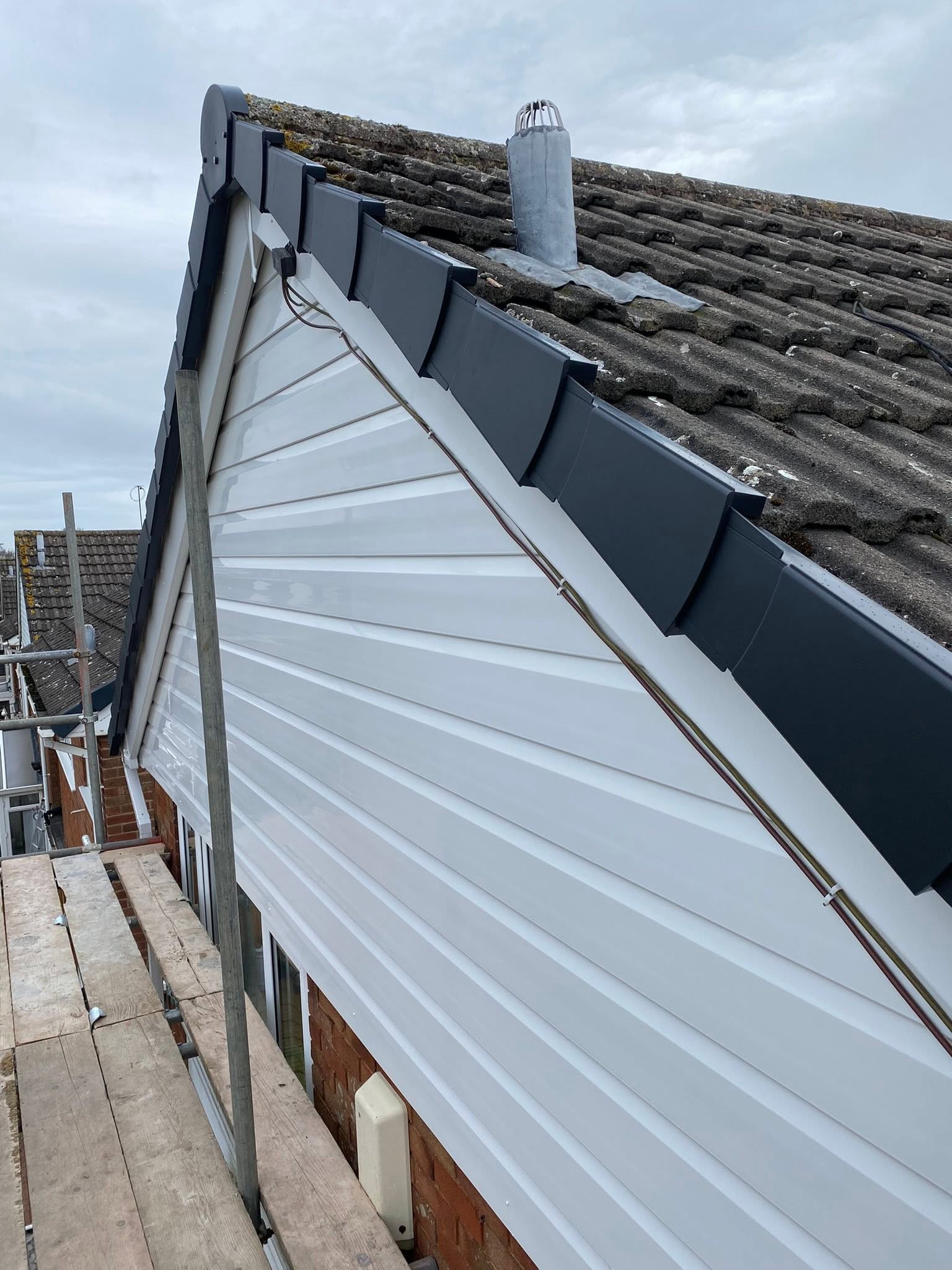 Dry ridge tile installation along roof apex with white UPVC cladding to gable — Wolverhampton